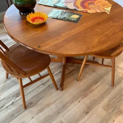 Sale Photo Thumbnail #91: Mid-century modern round wooden dining table with matching spindle-back chairs, featuring a warm finish and clean lines.