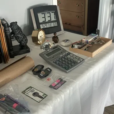 Sale Photo Thumbnail #166: Assorted desk accessories and office supplies, including a digital clock, a Spectra calculator, a small gold-tone clock, a bear figurine, and various writing utensils.