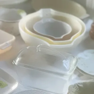 Sale Photo Thumbnail #106: Vintage Pyrex nesting mixing bowls in yellow and white tones, displayed alongside a clear glass butter dish and other assorted kitchenware.