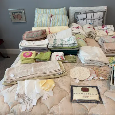 Sale Photo Thumbnail #131: Assortment of vintage and modern household linens, including embroidered towels, a Berkshire down alternative blanket, and delicate lace handkerchiefs, displayed on a Stearns & Foster mattress.