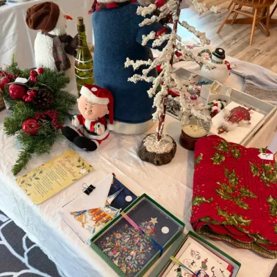 Sale Photo Thumbnail #193: Assortment of Christmas decorations featuring a large snowman figure in a blue coat, a frosted decorative tree, boxed holiday cards, and red quilted holly placemats.