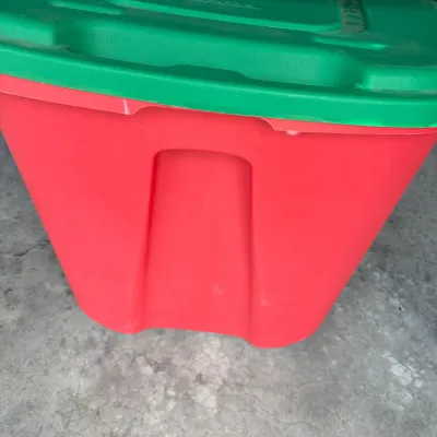Sale Photo Thumbnail #156: Large red plastic storage tote with a green lid, suitable for holiday decoration storage.