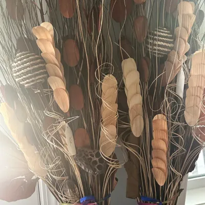 Sale Photo Thumbnail #72: Two decorative dried floral arrangements featuring wooden petals, woven rope spheres, and curly twigs tied with colorful ribbons.