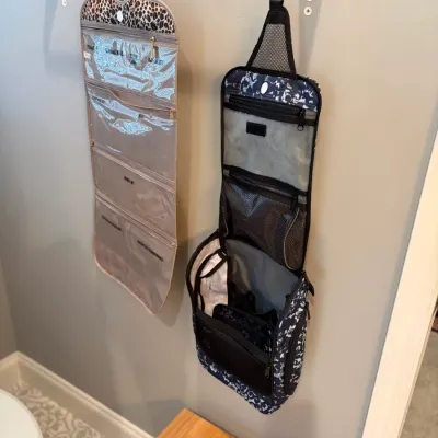 Sale Photo Thumbnail #160: Two hanging travel toiletry organizers, including a tan leopard-print model with clear pockets and a blue-and-white patterned organizer with multiple zippered compartments.