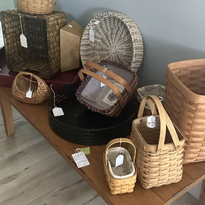 Sale Photo Thumbnail #136: Collection of woven baskets in various shapes and sizes, including several Longaberger-style wooden splint baskets with handles, displayed on a wooden table.