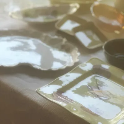 Sale Photo Thumbnail #104: Assorted vintage ceramic and glass tableware, including a square yellow plate with floral detail, a white scalloped platter, and amber glass bowls.