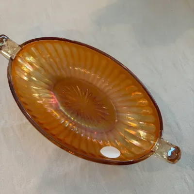 Sale Photo Thumbnail #58: Vintage marigold carnival glass oval relish dish featuring a ribbed pattern, starburst center, and dual handles.