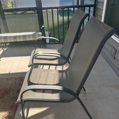 Sale Photo Thumbnail #173: Pair of modern outdoor patio chairs featuring dark metal frames and breathable grey mesh fabric seats.