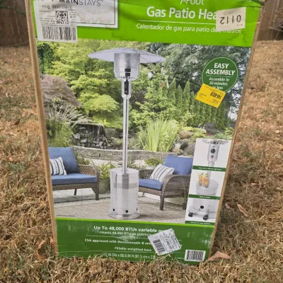 Sale Photo Thumbnail #215: Mainstays 7-foot gas patio heater in its original box. Features up to 48,000 BTUs variable output, CSA approval with thermocouple and anti-tilt safety devices, a fillable weighted base, and wheels for easy mobility. Dimensions listed on box are 32 in Dia 