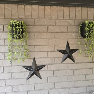 Sale Photo Thumbnail #205: A decorative wall set featuring two black semi-circular wall planters filled with trailing faux green foliage, paired with two matching black metal dimensional barn stars. Ideal for indoor or outdoor patio decor. Items show light outdoor wear but are in g