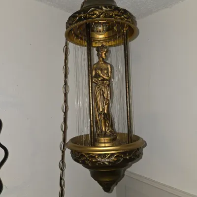 Sale Photo Thumbnail #177: A classic mid-century modern hanging rain lamp featuring a golden Greek goddess figurine at the center. The lamp is designed with a gold-toned metal frame, decorative ornate bands, and hanging monofilament lines for the oil-dripping effect. Includes a han