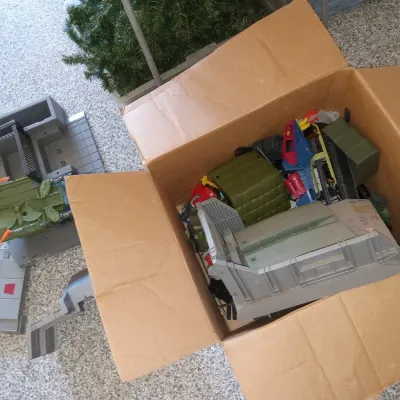 Assorted vintage G.I. Joe action figure playsets and vehicle parts, including elements of the Tactical Battle Platform, stored in a...