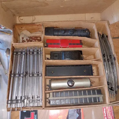 Vintage Lionel O-gauge model train set in its original cardboard box, featuring a steam locomotive, various freight cars, and sections of...
