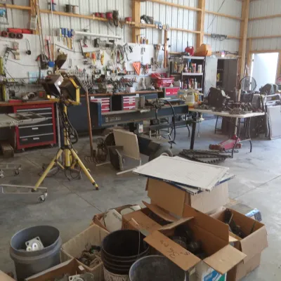 Assorted workshop tools, hardware, and equipment, including a log splitter, work lights, tool chests, and various storage bins filled...