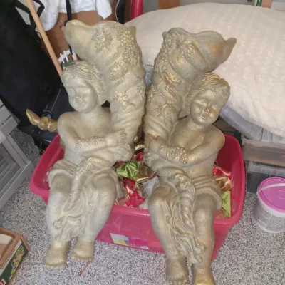 Pair of vintage cherub wall plaques with a gold-painted finish, each holding a cornucopia decorated with grapes and leaves.