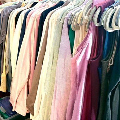 Sale Photo Thumbnail #79: Assorted women's clothing hanging on a rack, featuring a variety of colors and styles, alongside a shoe rack displaying various heels and flats.