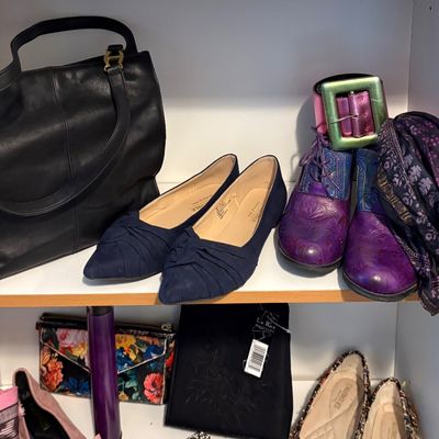 Sale Photo Thumbnail #88: Closet shelves displaying a variety of women's shoes and accessories, including navy blue flats, purple embossed leather boots, a black leather handbag, and patterned clutches.