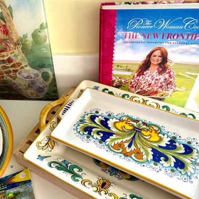 Sale Photo Thumbnail #90: Italian Deruta-style ceramic serving trays with vibrant hand-painted scroll designs, shown alongside a copy of "The Pioneer Woman Cooks: The New Frontier" cookbook.