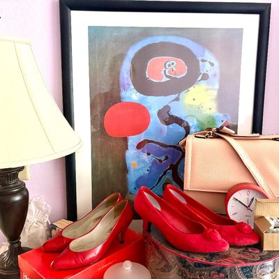 Sale Photo Thumbnail #60: Assorted vintage items including red heels, a pink shoulder bag, a small red desk clock, a table lamp, and a framed Joan Miro abstract art print.