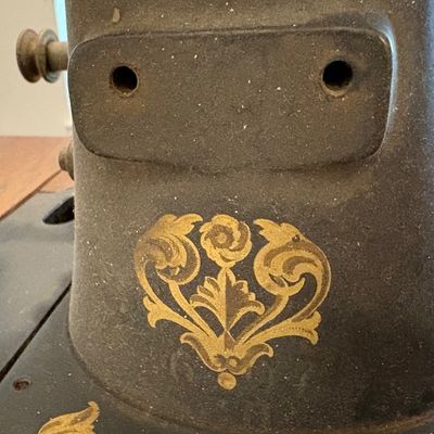 Sale Photo Thumbnail #68: Vintage Singer sewing machine detail showing a gold floral decal on a dusty black cast iron body.