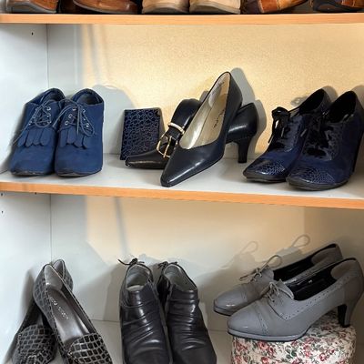 Sale Photo Thumbnail #78: Assortment of women's vintage and contemporary shoes, including pumps, booties, and loafers, displayed alongside small handbags on wooden shelves.