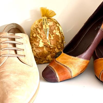 Sale Photo Thumbnail #74: Pair of beige suede men's dress shoes alongside a pair of multi-toned brown leather women's heels, with a Cedar Green sachet bag placed between them.