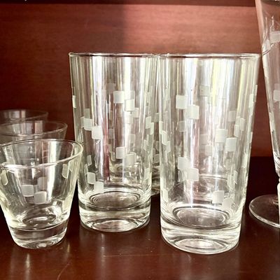 Sale Photo Thumbnail #103: Mid-century modern glassware set featuring a frosted square pattern, including highball glasses, shot glasses, and pilsner glasses.