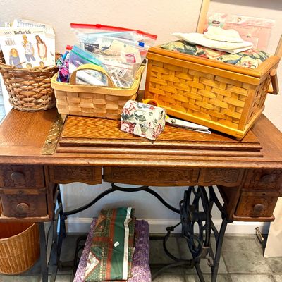 Sale Photo Thumbnail #65: Antique treadle sewing machine base repurposed as a table, topped with various sewing notions, baskets, and a vintage sewing box.