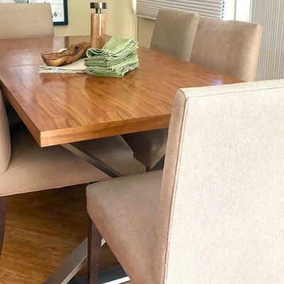 Contemporary dining set featuring a polished wood-top table with a metal base, paired with six upholstered high-back chairs in a neutral...