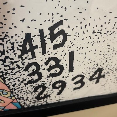 Close-up detail of a framed print showing a hand-lettered phone number in a stylized, stippled black-and-white design.