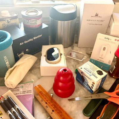 Assortment of household items, including a MudBuster dog paw cleaner, a red Kong dog toy, a travel adapter, Balsam Hill Miracle Flame...