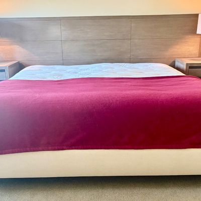 Contemporary king-size bedroom set featuring a wide, paneled wood headboard, two matching three-drawer nightstands, and a pair of modern...