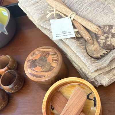 Assorted wooden tableware and linens, including a set of wooden napkin rings, a lidded container with inlaid wood design, cheese knives...