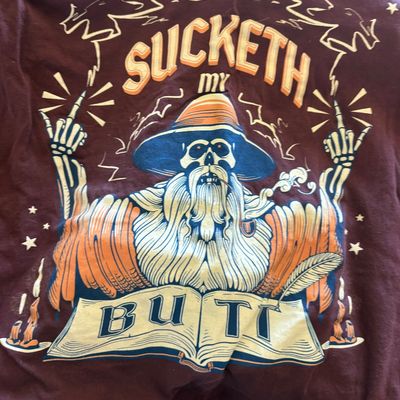 Novelty graphic t-shirt featuring a skeletal wizard illustration with the humorous phrase "Sucketh My Butt."