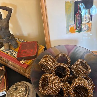 Assorted vintage tabletop decor, including a collection of beaded napkin rings in a glass bowl, a small female figure sculpture, old...