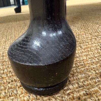 Close-up of a dark-stained wooden furniture leg with a bulbous foot, resting on a woven sisal rug.