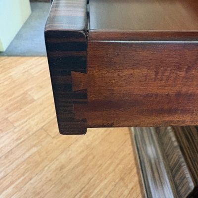 Dovetail joint detail on a wooden drawer, showcasing quality craftsmanship and rich wood grain.
