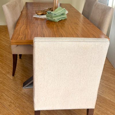 Contemporary dining set featuring a rectangular wood-grain table with a metal base, paired with six upholstered high-back chairs in a...