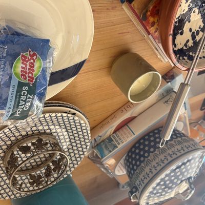 Assorted kitchenware and tableware, including a teal Le Creuset dish, patterned ceramic plates, a covered casserole dish, and a teal...