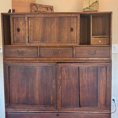 Japanese tansu chest in a dark wood finish, featuring sliding doors, multiple drawers with traditional metal pulls, and open cubbies.