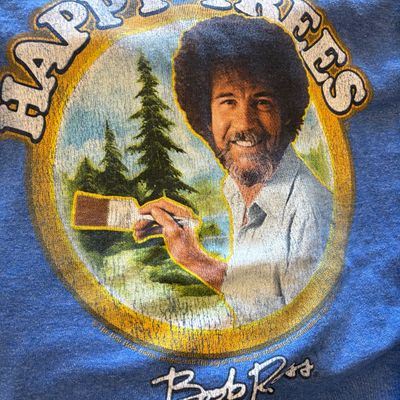 Bob Ross "Happy Trees" graphic t-shirt in heather blue, featuring a distressed print of the artist painting.