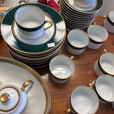 Vintage porcelain tea set featuring a deep green and gold band design, including cups, saucers, plates, and a lidded sugar bowl.
