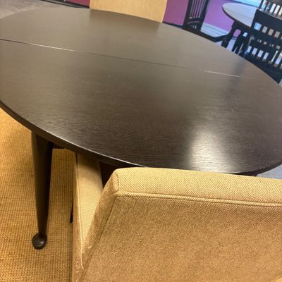 Contemporary dark wood round dining table paired with upholstered beige fabric chairs.
