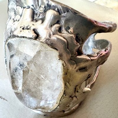 Vintage brutalist sterling silver ring featuring a large, raw-cut clear quartz crystal in a heavy, textured setting.