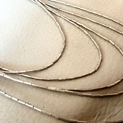 Multi-strand liquid silver necklace featuring delicate cylindrical beads, showing a light patina.