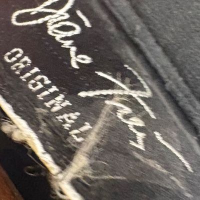 Vintage "Jane Kay Original" embroidered label on a black fabric item, showing some wear and fraying.