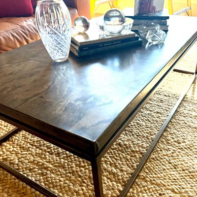 Industrial-style coffee table featuring a dark metal top and a matching open metal frame, styled with books and crystal decor.