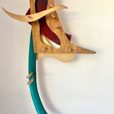 Abstract mixed-media wall sculpture constructed from layered plywood, painted wood elements, and yellow pencils with pink erasers.