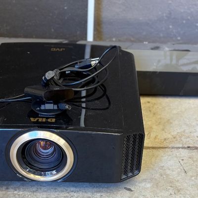 JVC D-ILA home theater projector in a glossy black finish, complete with power cord and sensor accessory.