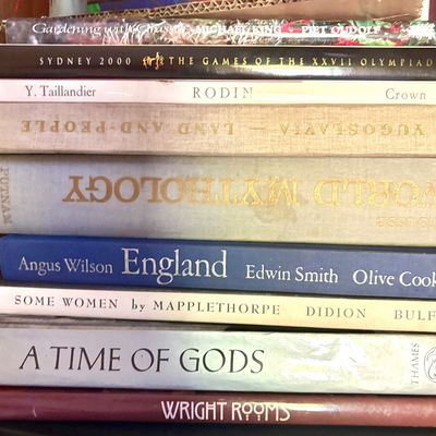 Stack of vintage and modern hardcover coffee table books, featuring titles on art, mythology, photography, and travel.